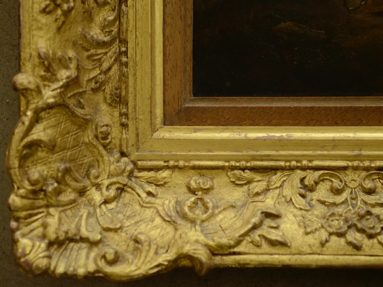 Corner of an ornate antique gilt frame showing surface wear ahead of restoration