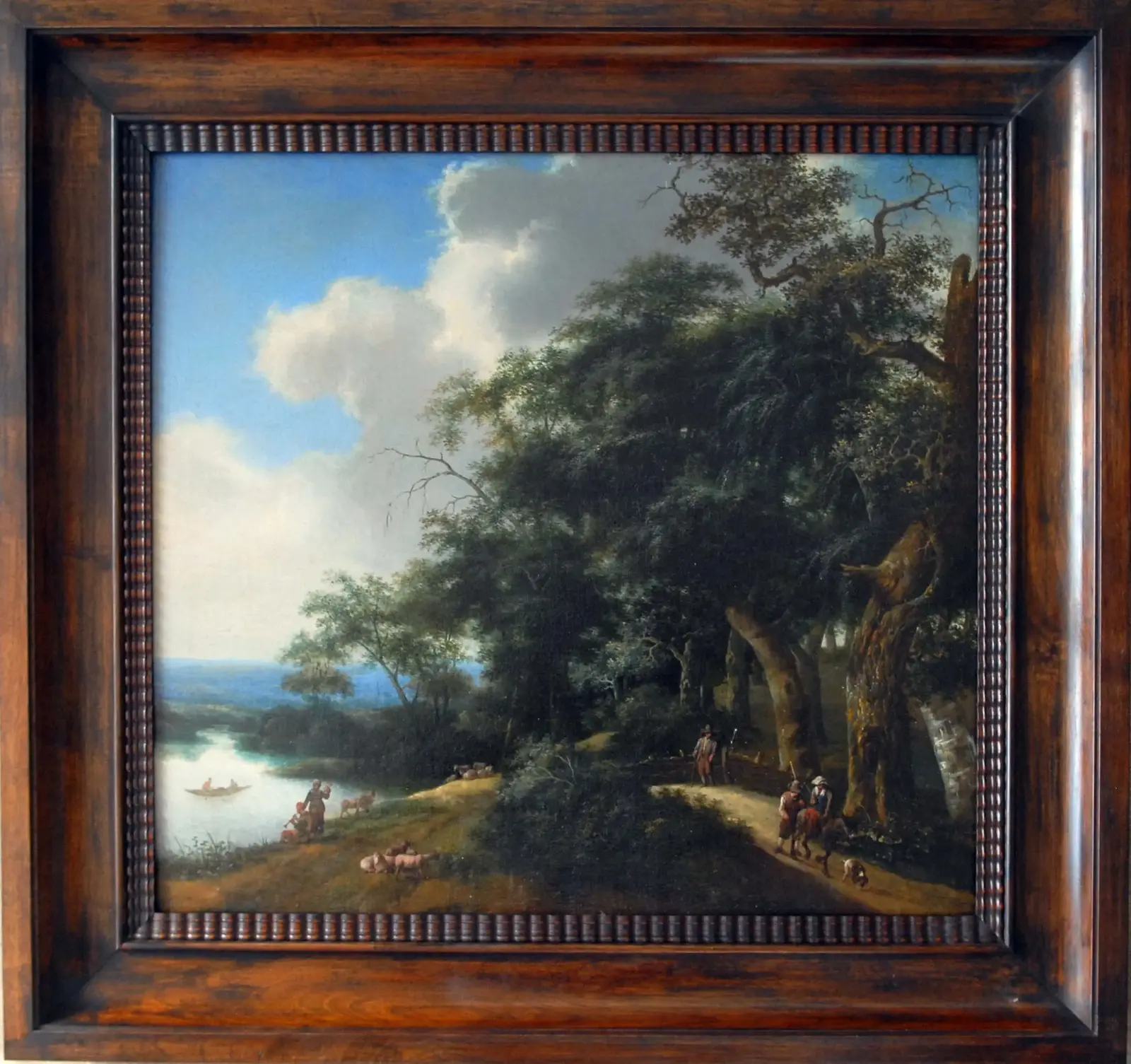 A framed oil landscape painting in a handmade reeded dark wood frame