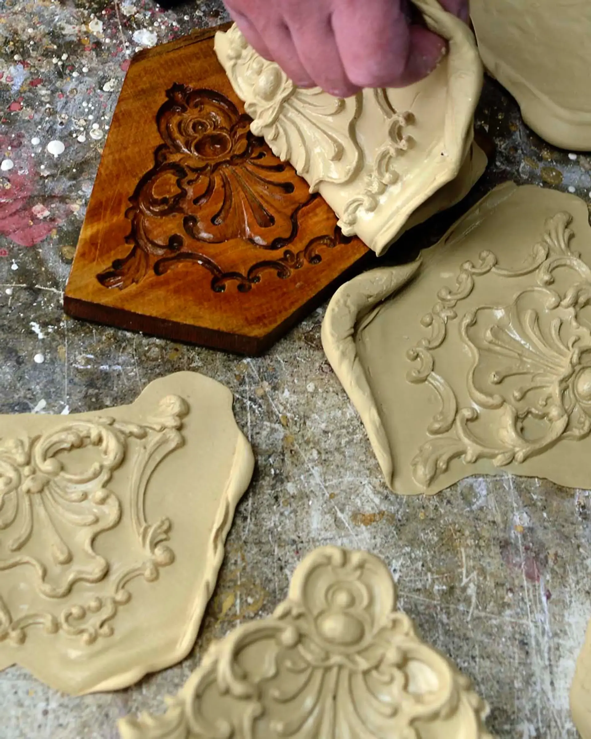 A craftsman's hand pressing compo into a carved wooden ornament mould in our studio
