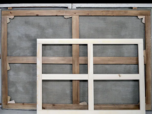 An older, aged canvas stretcher alongside a newly handmade stretcher in pale timber, showing the contrast after years of use