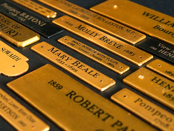 Hand engraving lettering into a gold leaf plaque